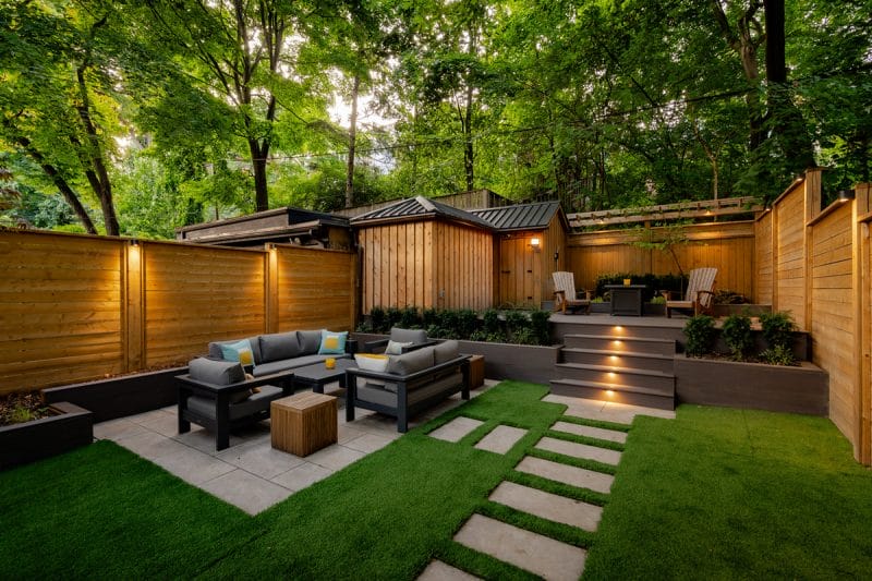 Landscaping with a composite deck, patio, retaining walls, custom planters, and new fence installation.