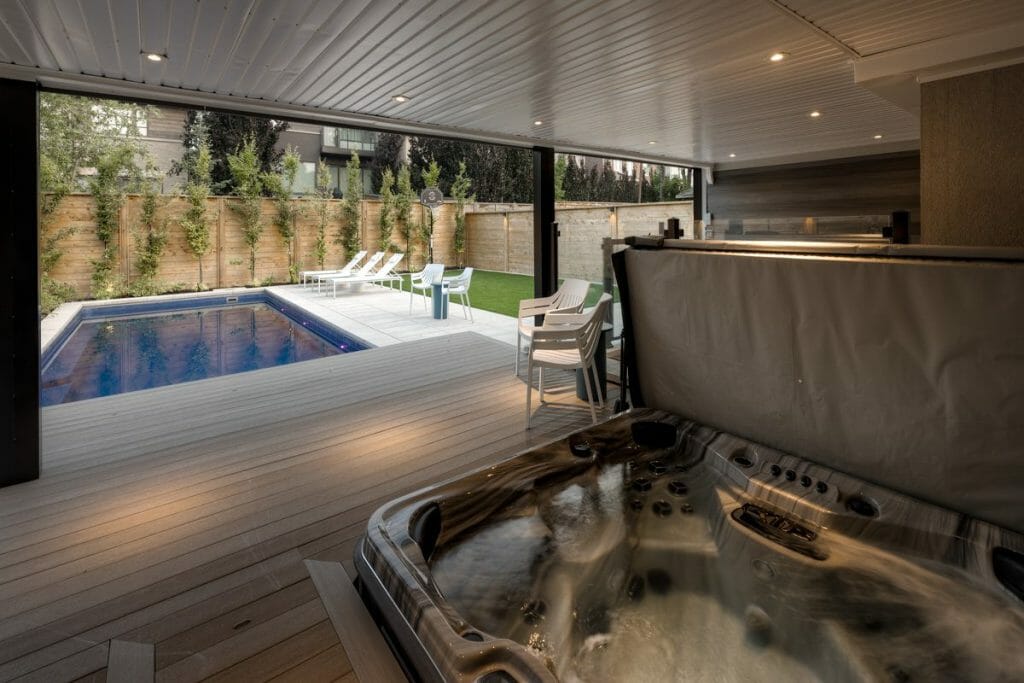 M.E. Contracting's Backyard landscaping construction Project feature Lower-Level PVC Deck with Glass Railings, Swim Spa, Stone Patio, and Artificial Grass