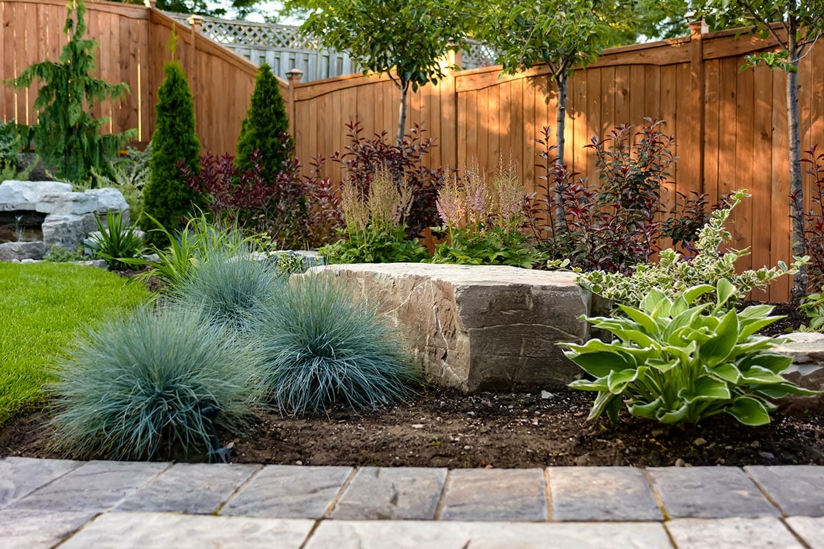 landscaping design and construction by M.E. contracting feature armor stone, interlocking, shrubs and fence installed 