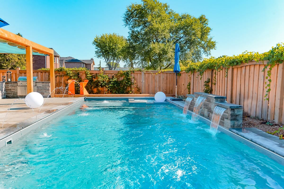 Fiberglass Pool with Water Features Installation & Landscape Design; Featuring Pergola & Interlocking by Toronto Landscaping Company.