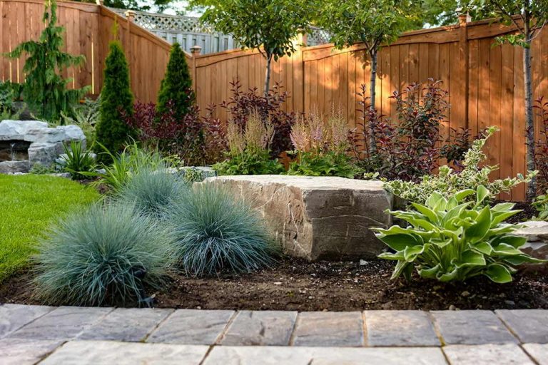 landscaping design and construction by M.E. contracting feature armor stone, interlocking, shrubs and fence installed
