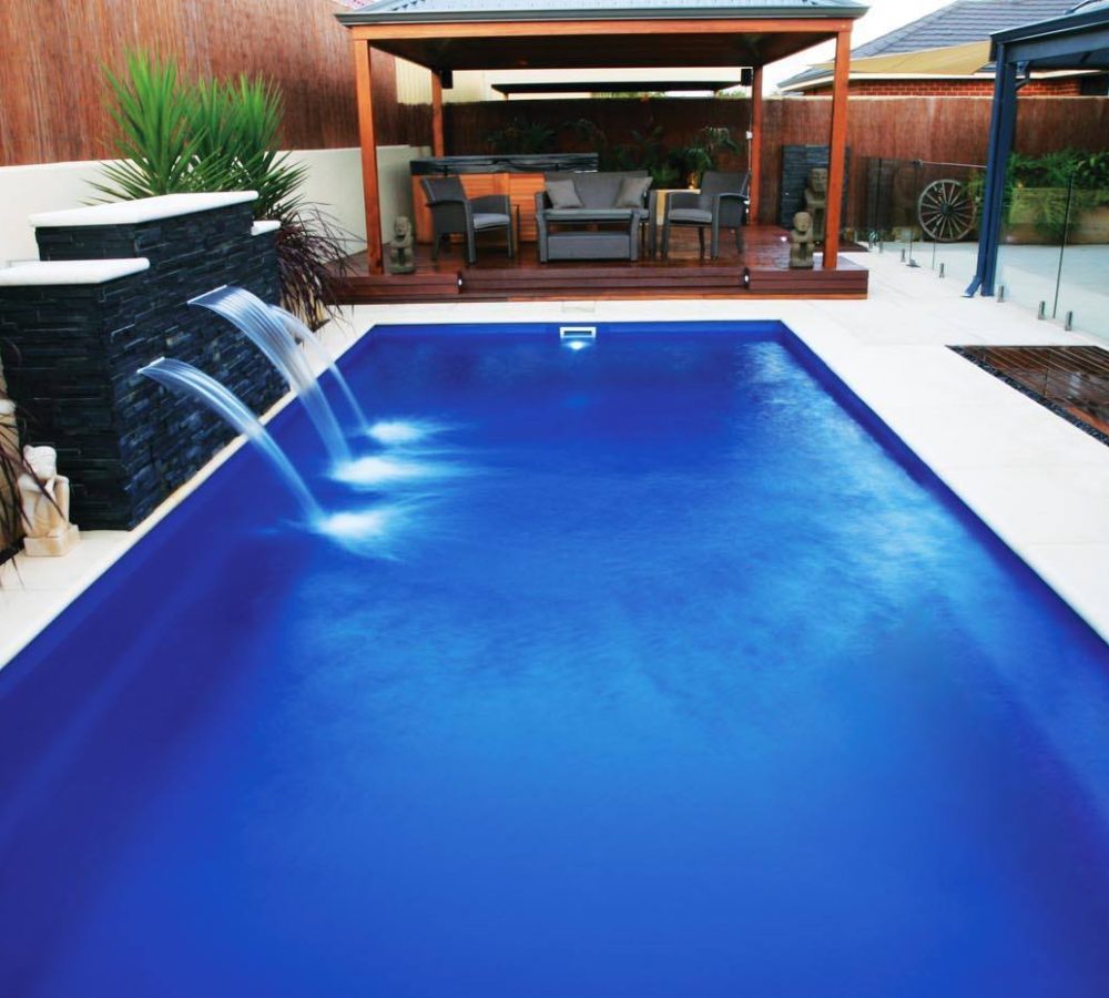 The Reflection Fiberglass pool with coping, pergola and water feature by M.E. contracting